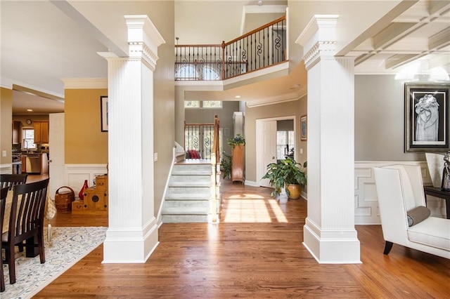 foyer entrance featuring a healthy amount of sunlight, wood finished floors, and ornate columns