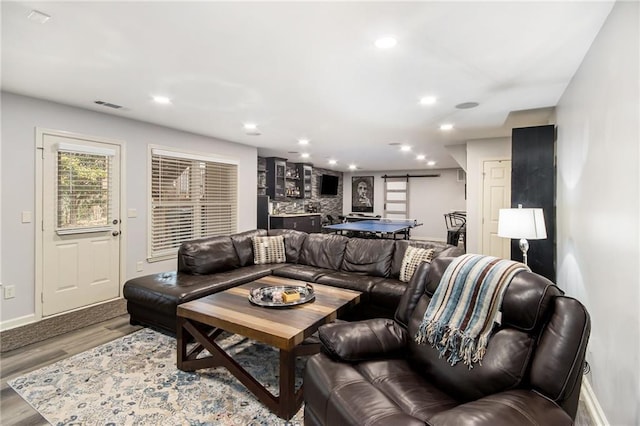 living area featuring a barn door, wood finished floors, visible vents, and recessed lighting