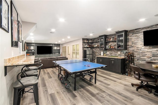 rec room featuring recessed lighting, light wood-style flooring, and wet bar