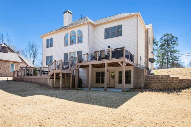 back of house featuring a deck, a patio, and a chimney