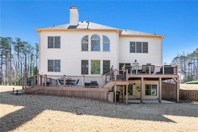 back of property featuring a patio area, a chimney, and a wooden deck