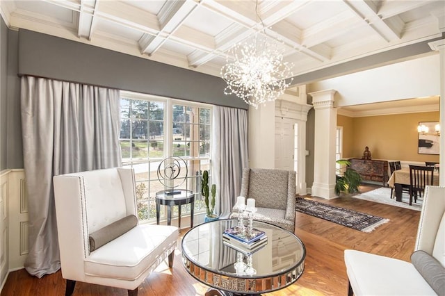 sitting room featuring beam ceiling, wood finished floors, decorative columns, and a notable chandelier