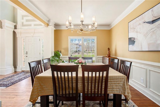 dining space featuring ornamental molding, wood finished floors, and an inviting chandelier