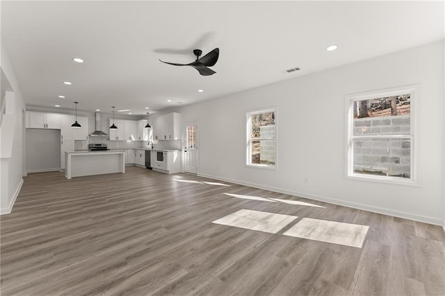 unfurnished living room featuring ceiling fan and light hardwood / wood-style floors