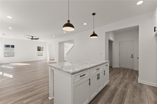 kitchen with hanging light fixtures, ceiling fan, light stone countertops, and white cabinetry