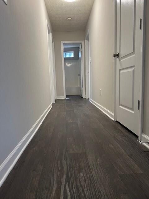 hallway with dark wood-type flooring and a textured ceiling