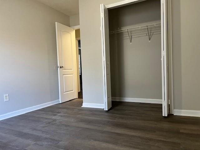 unfurnished bedroom with a closet and dark hardwood / wood-style floors