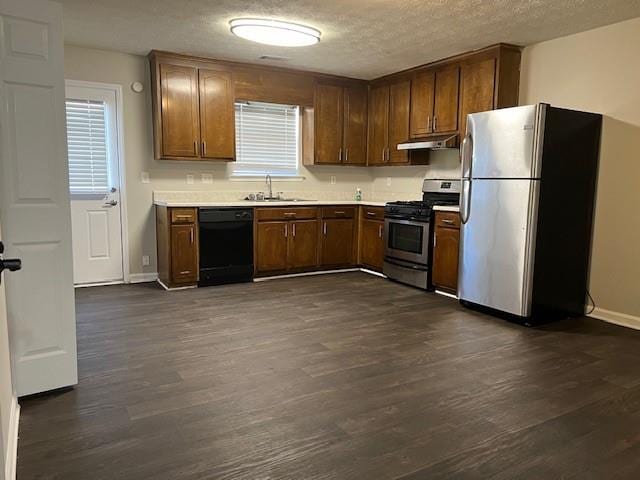 kitchen featuring appliances with stainless steel finishes, dark hardwood / wood-style floors, sink, and a textured ceiling