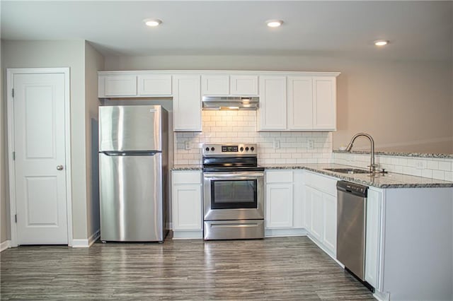 kitchen featuring sink, white cabinetry, kitchen peninsula, appliances with stainless steel finishes, and dark stone countertops