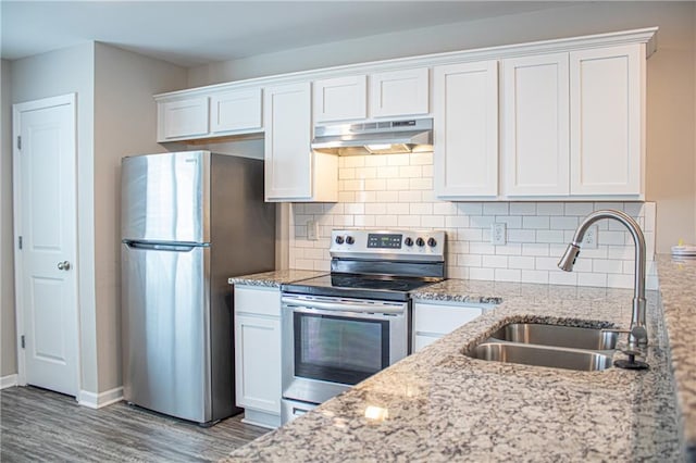 kitchen with sink, white cabinetry, appliances with stainless steel finishes, light stone countertops, and hardwood / wood-style floors