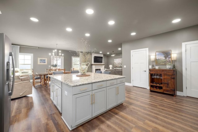 kitchen featuring stainless steel refrigerator with ice dispenser, open floor plan, a center island, recessed lighting, and dark wood-style flooring