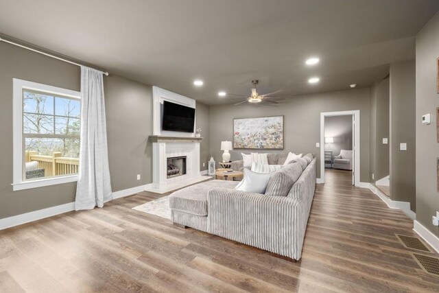 living area with baseboards, recessed lighting, wood finished floors, ceiling fan, and a high end fireplace