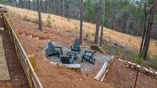 view of yard with a fire pit and a wooded view
