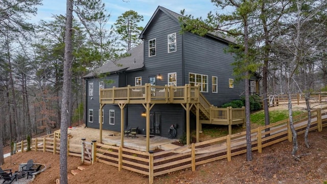 rear view of house featuring a deck, fence, stairway, and roof with shingles