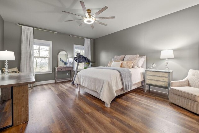 bedroom with dark wood finished floors, a ceiling fan, and baseboards