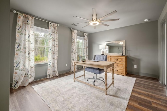 office area with a ceiling fan, dark wood-type flooring, and baseboards