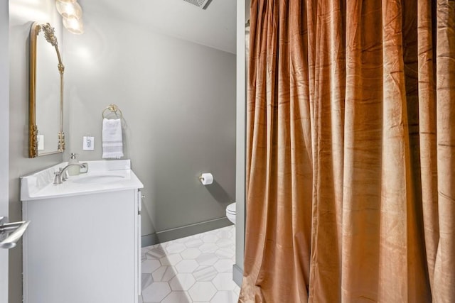 bathroom featuring vanity, toilet, tile patterned floors, and baseboards