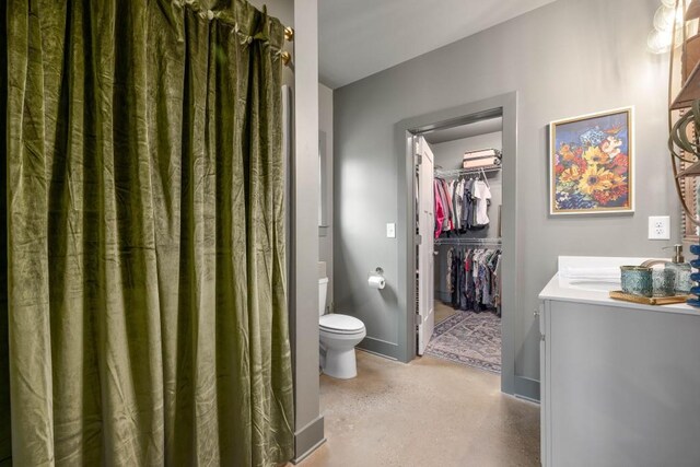 full bath featuring toilet, vanity, and a walk in closet
