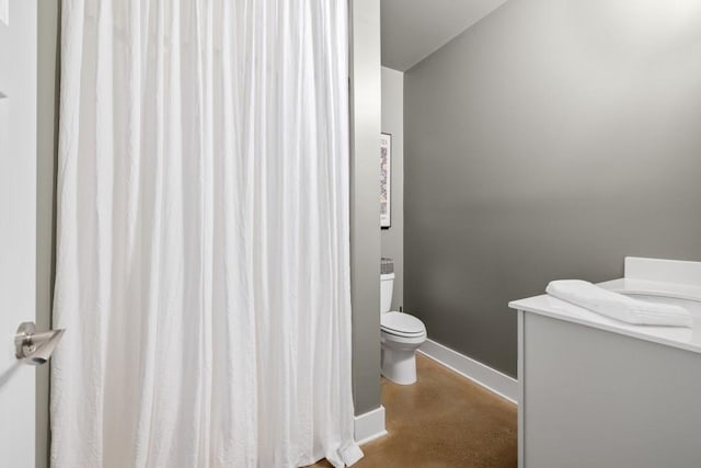 bathroom with toilet, baseboards, and finished concrete flooring