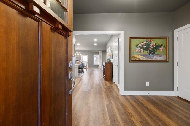 hallway with wood finished floors, baseboards, and recessed lighting