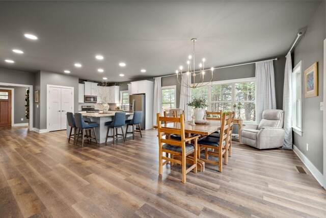 dining area with a chandelier, recessed lighting, wood finished floors, and baseboards