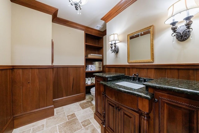 bathroom featuring toilet, vanity, crown molding, and wooden walls