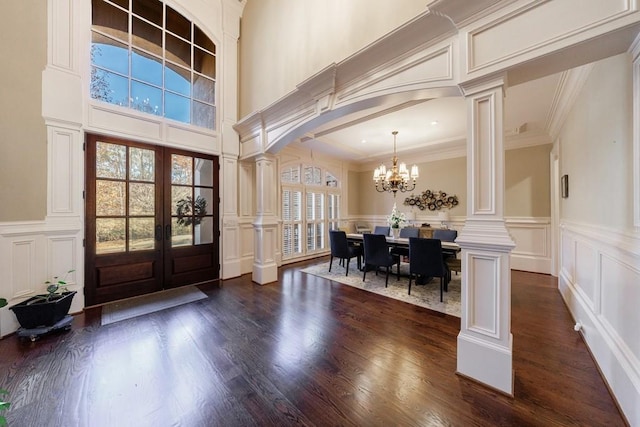 foyer entrance with decorative columns and dark wood-type flooring