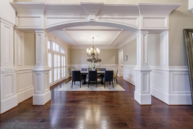 dining area with a chandelier, dark hardwood / wood-style floors, ornate columns, and ornamental molding