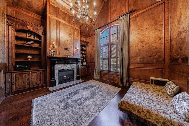 sitting room featuring wooden walls, built in features, a high end fireplace, and dark hardwood / wood-style floors