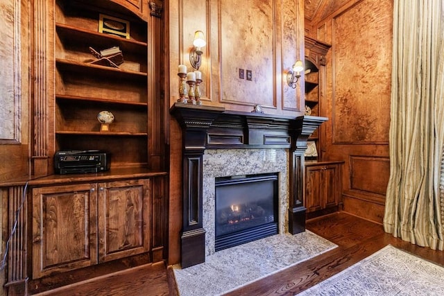 details featuring a premium fireplace, wooden walls, and wood-type flooring