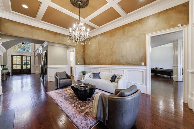 living room with decorative columns, french doors, dark hardwood / wood-style floors, ornamental molding, and a chandelier