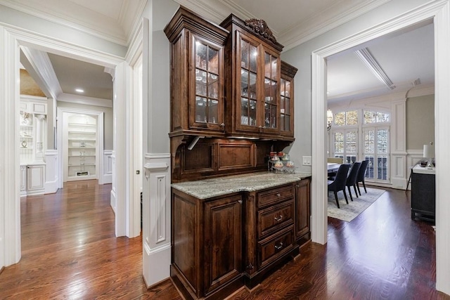 bar with crown molding, light stone counters, dark brown cabinetry, and dark wood-type flooring