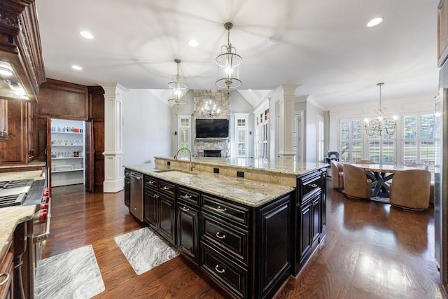 kitchen with a large island, sink, dishwasher, dark wood-type flooring, and decorative light fixtures