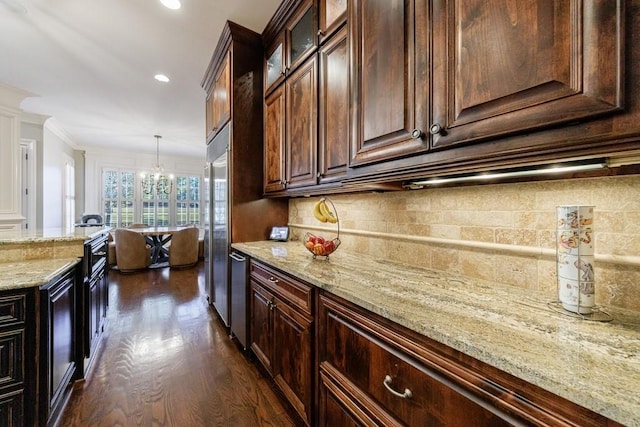 kitchen with dark brown cabinetry, hanging light fixtures, dark hardwood / wood-style flooring, stainless steel built in fridge, and ornamental molding