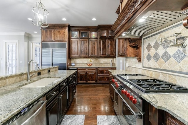 kitchen with decorative backsplash, ornamental molding, custom range hood, sink, and high quality appliances