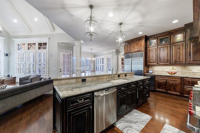 kitchen featuring ornate columns, sink, stainless steel appliances, pendant lighting, and dark brown cabinets