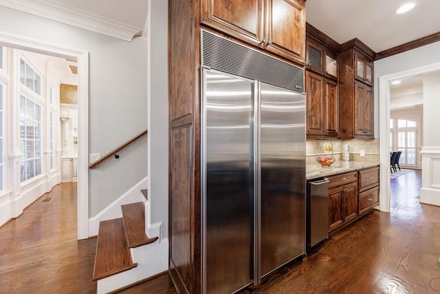 kitchen featuring dark hardwood / wood-style flooring, light stone counters, built in fridge, and crown molding