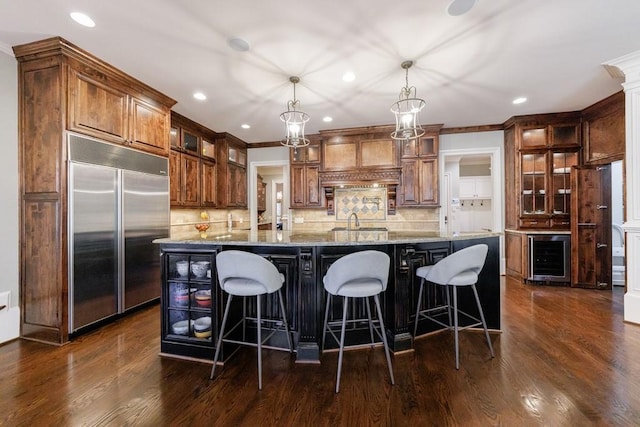 kitchen featuring built in refrigerator, dark wood-type flooring, beverage cooler, and decorative light fixtures