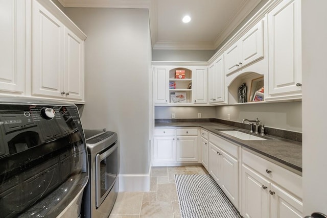 clothes washing area featuring washing machine and dryer, crown molding, sink, and cabinets