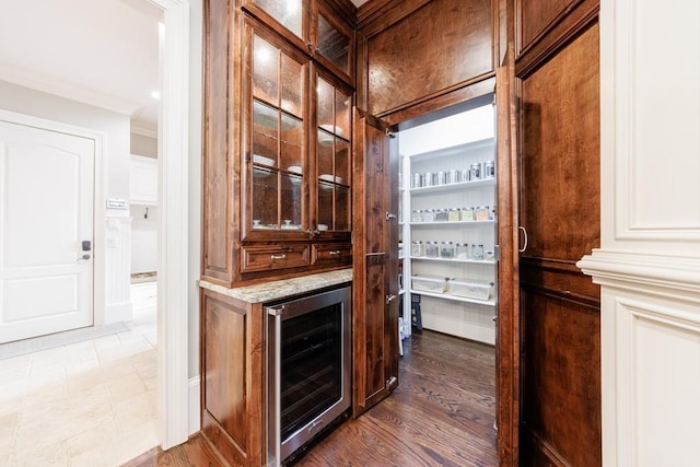 bar with ornamental molding, beverage cooler, and wood-type flooring