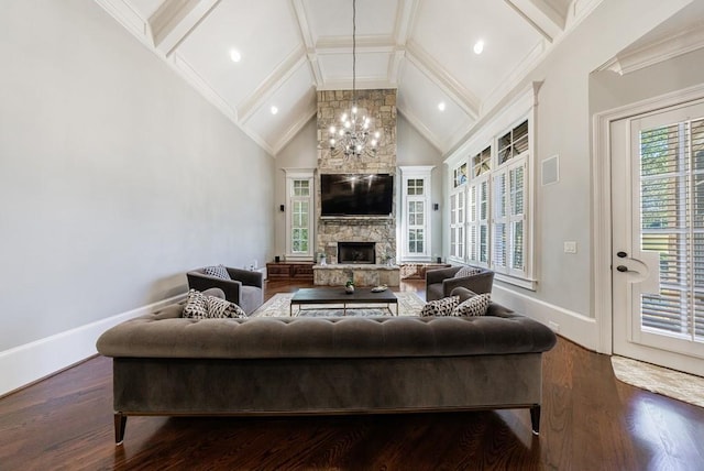 living room featuring lofted ceiling, hardwood / wood-style flooring, ornamental molding, a fireplace, and a notable chandelier