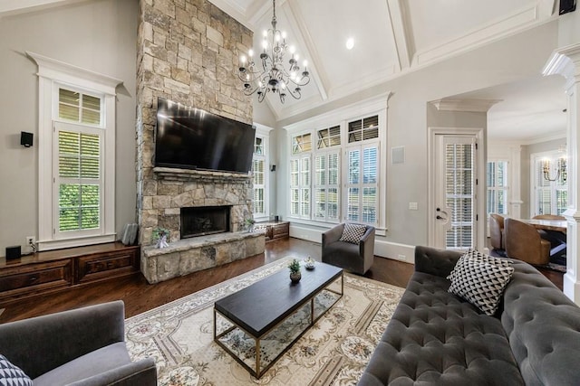 living room with hardwood / wood-style floors, plenty of natural light, a stone fireplace, and an inviting chandelier