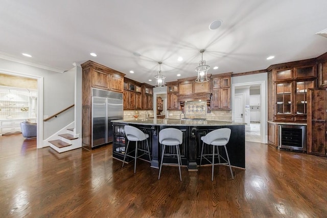 kitchen featuring hanging light fixtures, stainless steel appliances, a spacious island, decorative backsplash, and a breakfast bar