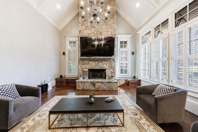 living room with high vaulted ceiling, a stone fireplace, crown molding, a notable chandelier, and dark hardwood / wood-style flooring