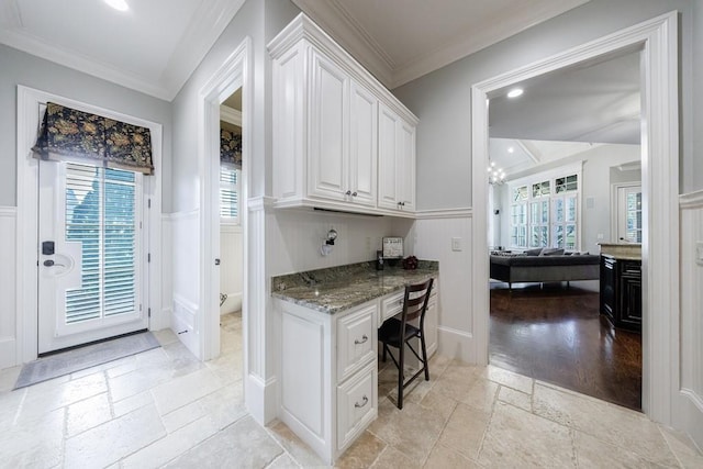 office space with built in desk, light wood-type flooring, and crown molding