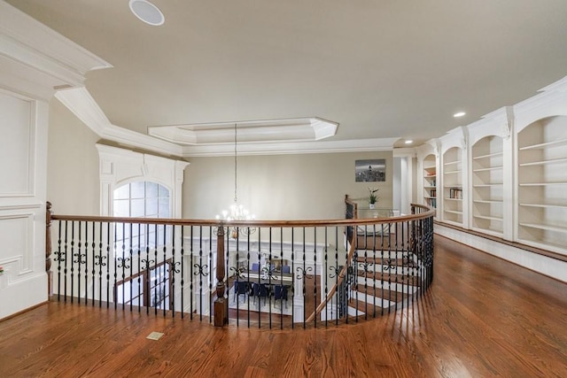 hall with hardwood / wood-style floors, a tray ceiling, an inviting chandelier, and ornamental molding