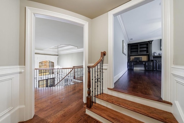 stairway featuring ornamental molding, a notable chandelier, and hardwood / wood-style flooring