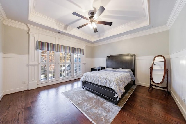 bedroom featuring ornamental molding, a tray ceiling, ceiling fan, and dark wood-type flooring