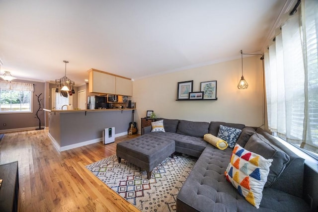 living room with crown molding, light hardwood / wood-style flooring, and a chandelier