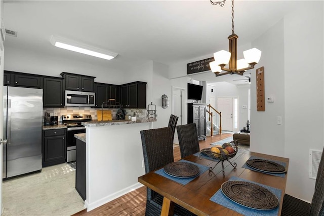 kitchen with tasteful backsplash, decorative light fixtures, a chandelier, kitchen peninsula, and stainless steel appliances